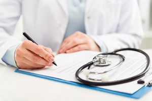 Young woman physician with stethoscope prescribing treatment